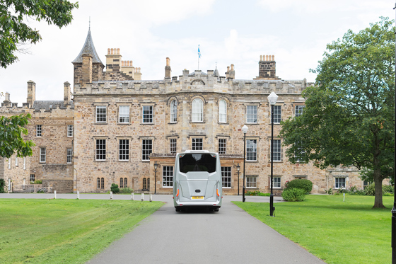 A bus from Anderson Black Executive Travel's fleet drives down driveway towards wedding venue