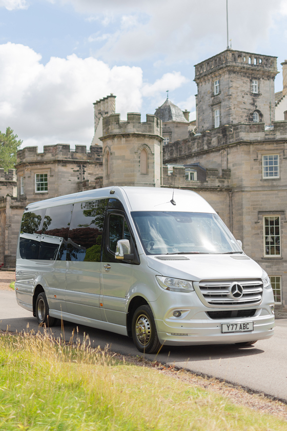 Minibus from Anderson Black Executive Travel with castle and blue skies in background