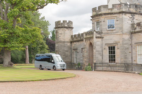 An Anderson Black Executive Travel minibus parked on path of Scottish castle wedding venue