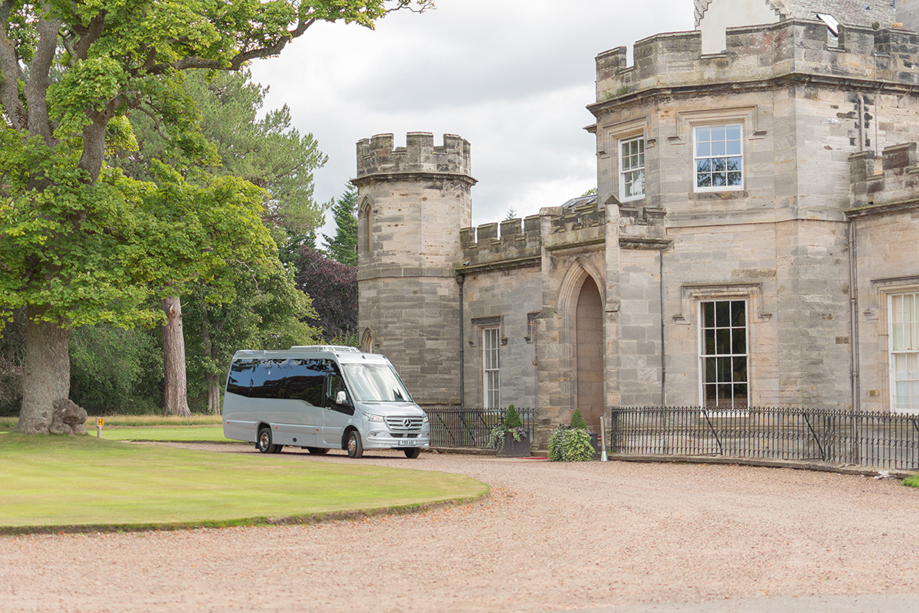 An Anderson Black Executive Travel minibus parked on path of Scottish castle wedding venue