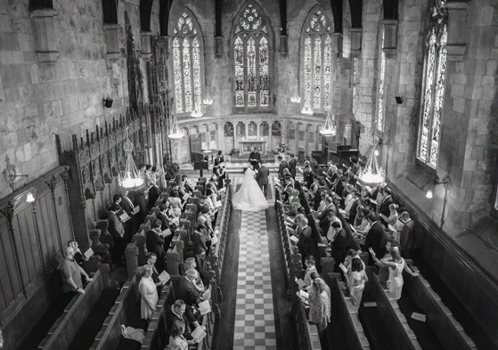 Overhead black and white view of a church wedding ceremony planned by DSW Weddings, with guests seated in wooden pews