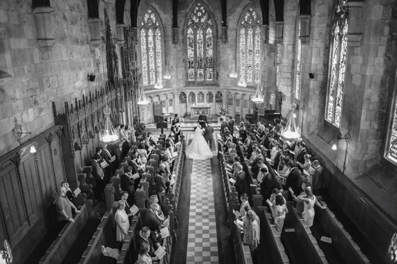 Overhead black and white view of a church wedding ceremony planned by DSW Weddings, with guests seated in wooden pews