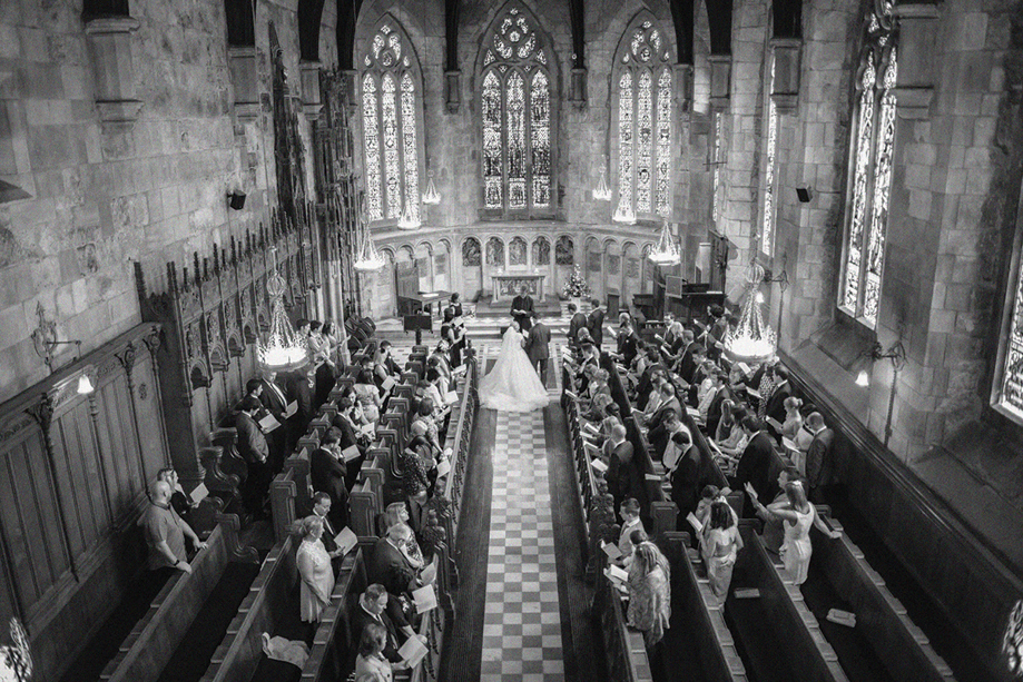 Overhead black and white view of a church wedding ceremony planned by DSW Weddings, with guests seated in wooden pews