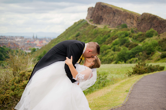 Bride and groom sharing a kiss outdoors with dramatic hillside scenery, coordinated by DSW Weddings