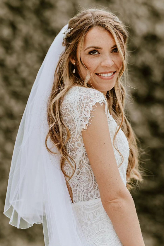 Bride posing outdoors with soft, natural bridal makeup and loose hair styled for a relaxed wedding look