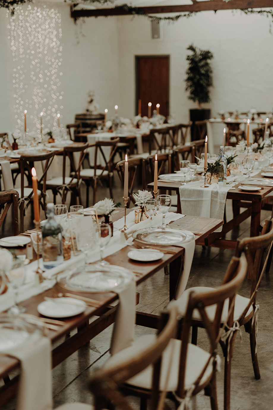 Rustic long-table wedding styling with wooden chairs, candlelight and neutral linen decor at a Scottish barn reception
