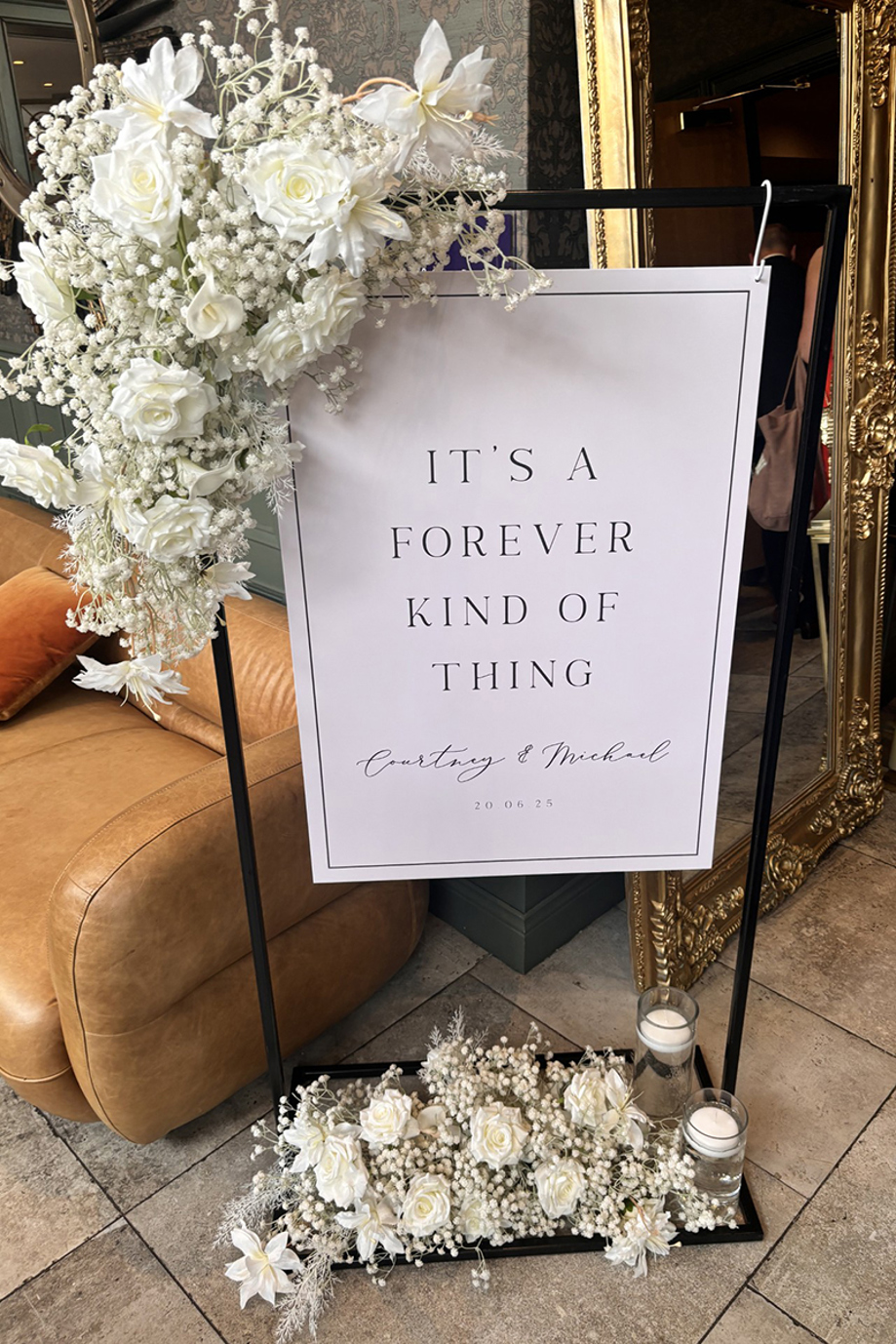 Modern wedding welcome sign on black stand with white florals and candles, personalised for Courtney and Michael