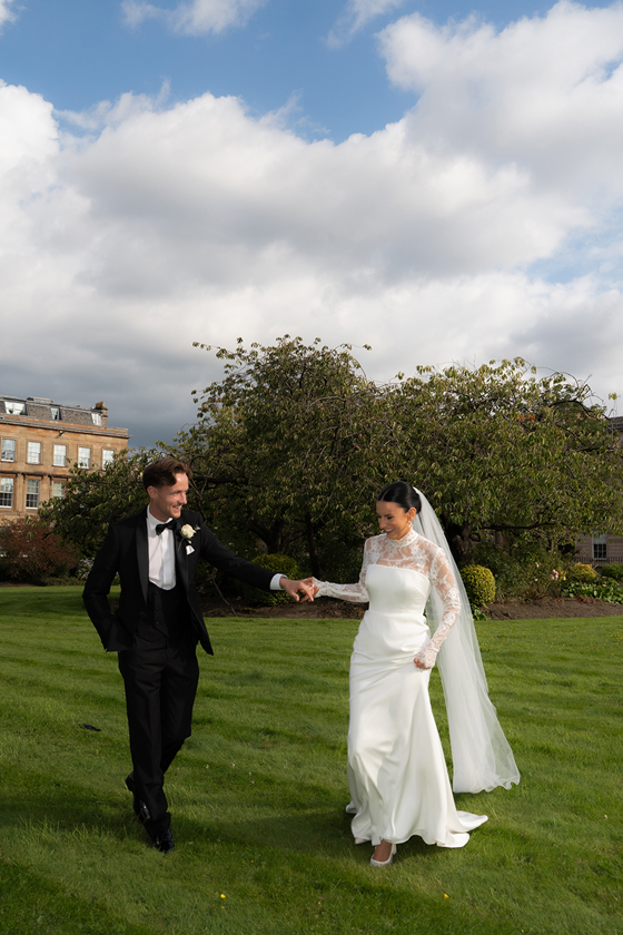 Bride and groom walking across lawn at estate garden wedding venue outdoor portrait