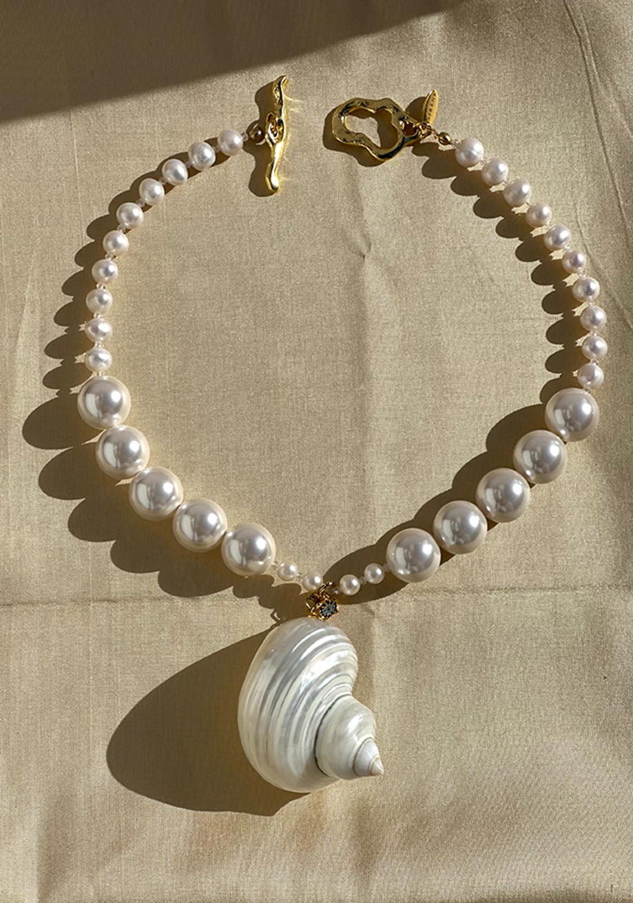 Chunky freshwater pearl statement necklace with shell pendant on beige linen