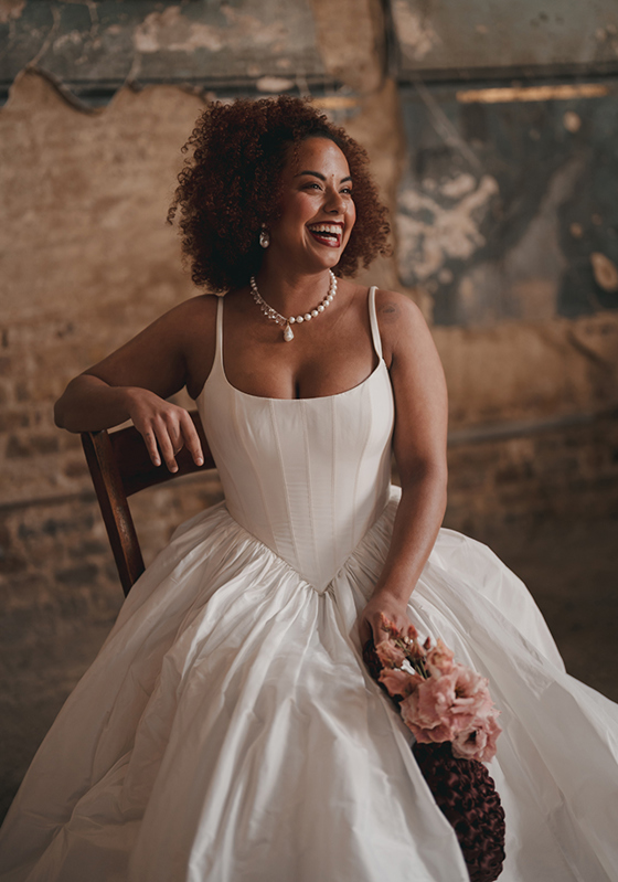 Smiling bride in corset wedding dress wearing pearl necklace with pendant