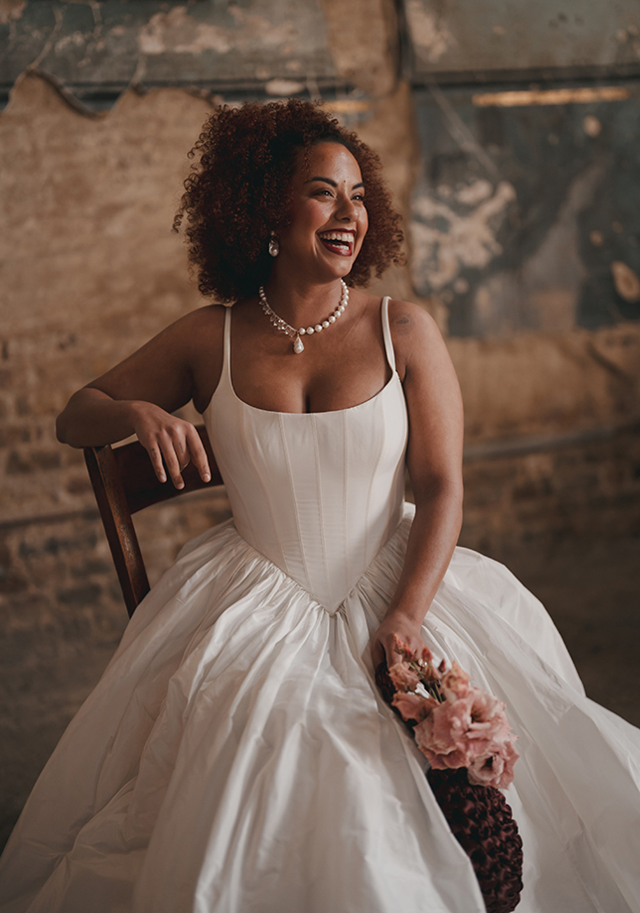 Smiling bride in corset wedding dress wearing pearl necklace with pendant