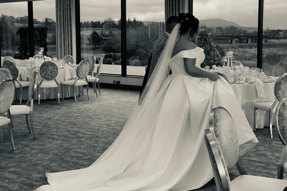 Black and white wedding content image of bride and groom walking into their wedding breakfast reception captured by Effortless Ivory Weddings