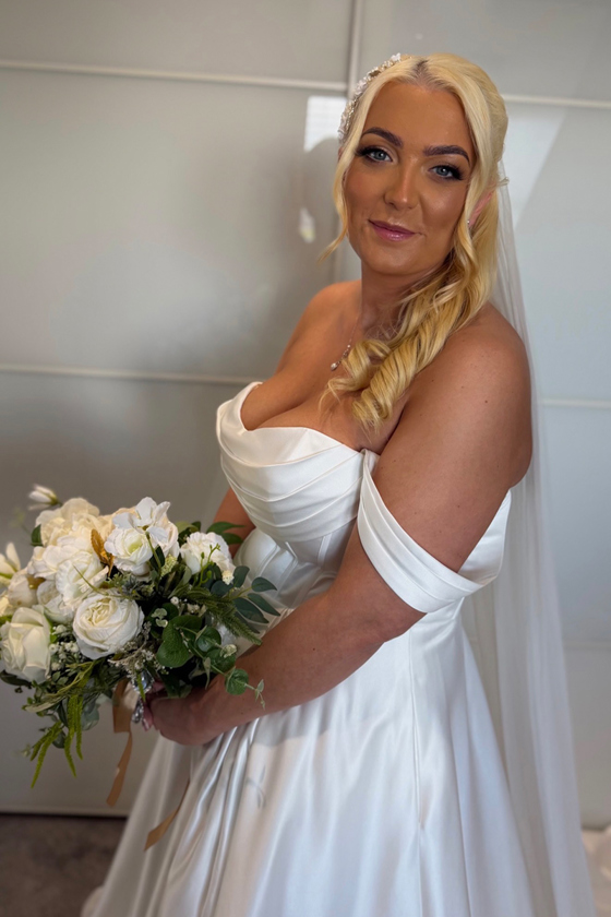Blonde bride holding bouquet wears strapless wedding dress and smiles at camera, captured by Arauthentic Moments