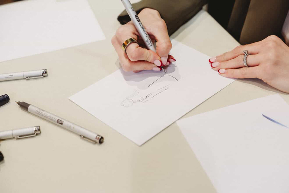 Close-up of Colleen sketching a personalised live wedding guest illustration using pen and paper.