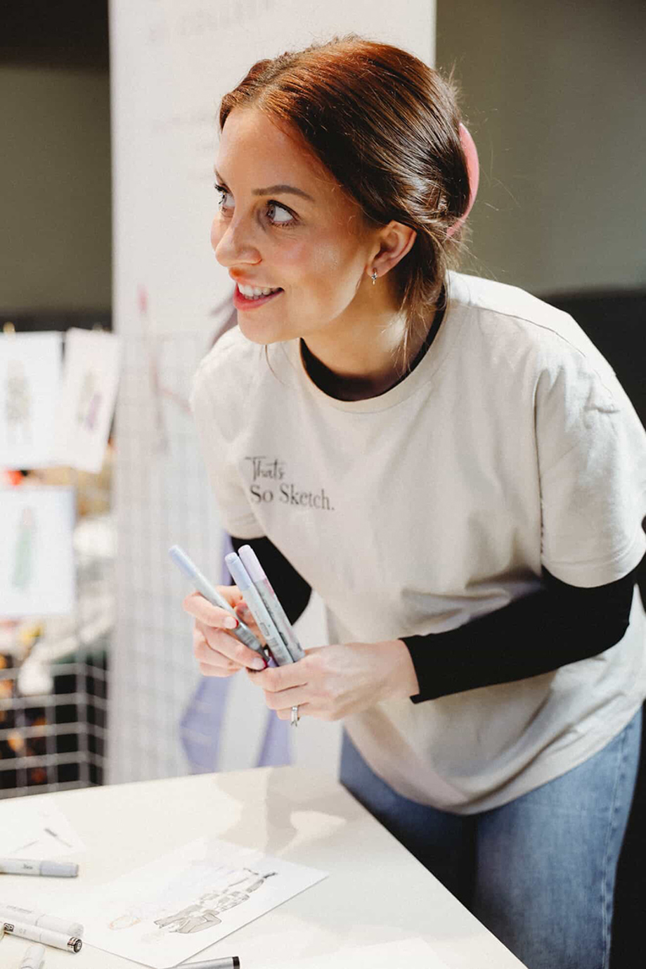 Live wedding illustrator Colleen from That’s So Sketch holding markers while creating guest portraits during a wedding.