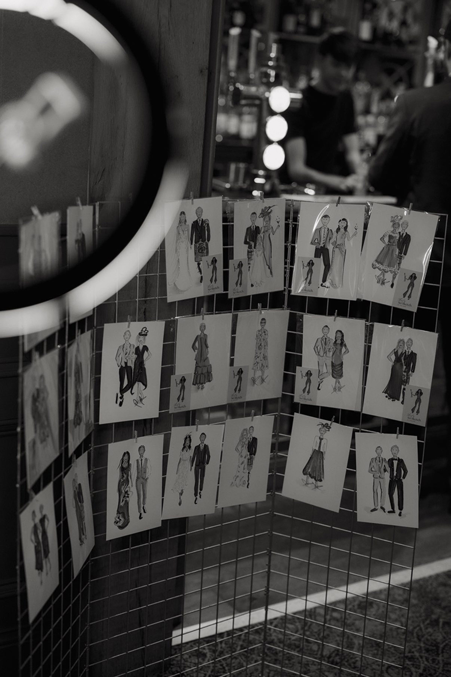 Display board featuring multiple hand-drawn live wedding guest illustrations by That’s So Sketch.