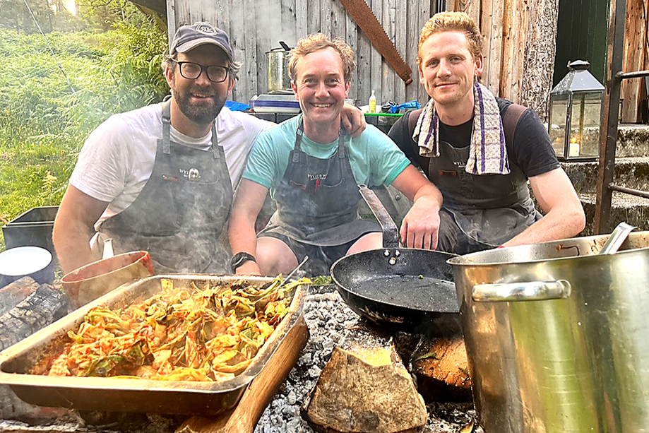 The Wylie & Wood team preparing food over open fire cooking equipment during an outdoor Scottish catering event.