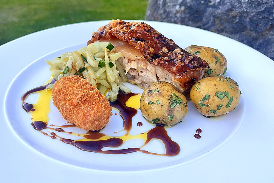 Plated pork dish with potatoes, vegetables and croquette served by Wylie & Wood as part of a luxury catering menu.