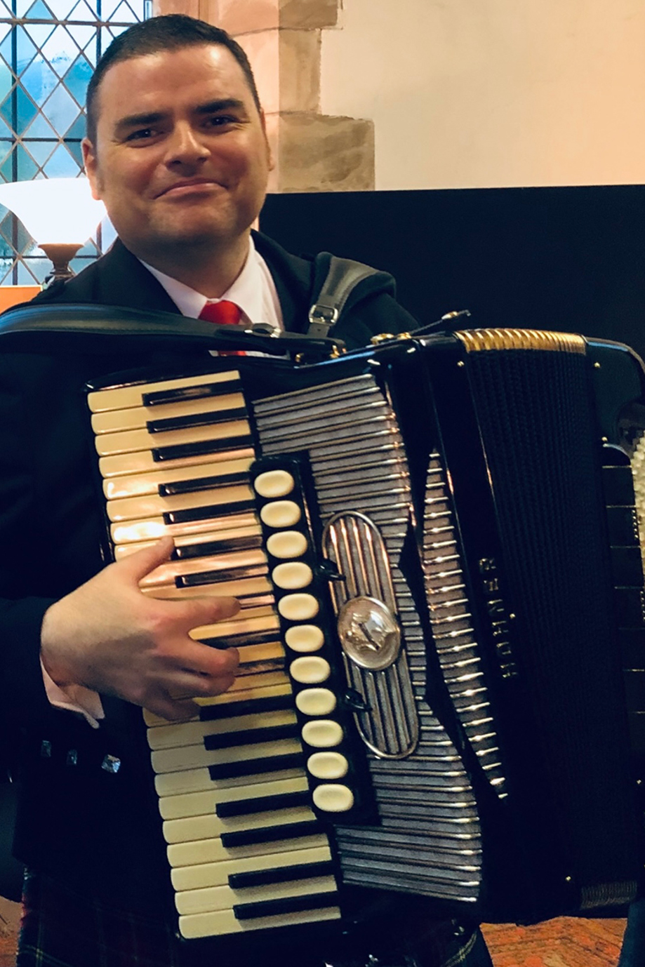 Accordion player performing live indoors at a wedding venue in Scotland.