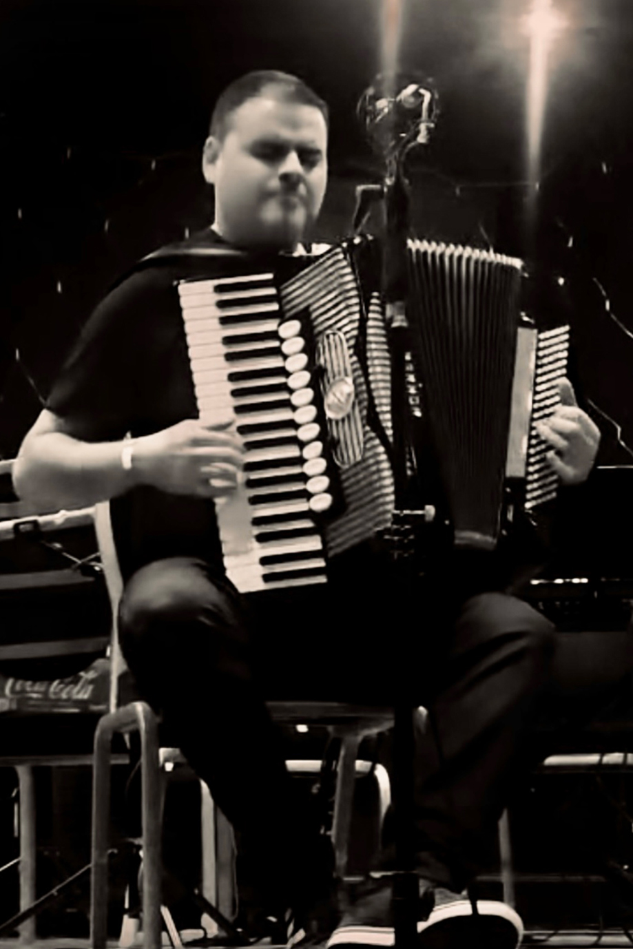 Accordion musician performing on stage during a live Scottish music event.