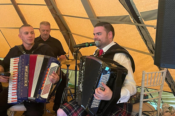 Scottish ceilidh musicians performing live inside a marquee wedding reception.