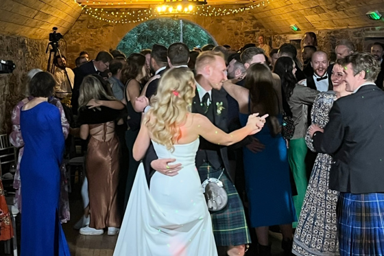 Busy wedding dance floor filled with guests dancing during evening entertainment.