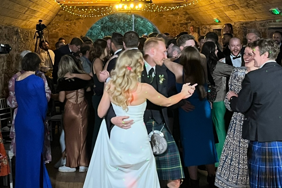 Busy wedding dance floor filled with guests dancing during evening entertainment.