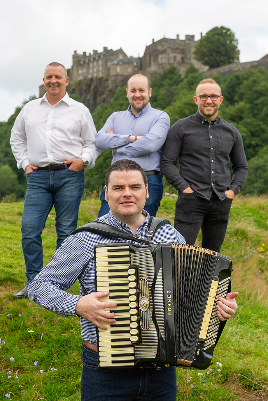 Members of The Liam Stewart Band posing outdoors with Edinburgh Castle in the background.