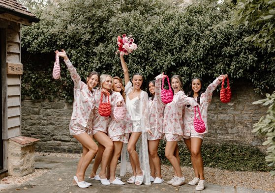 bridesmaids and bride on wedding day in their pyjamas holding a bridal handbag