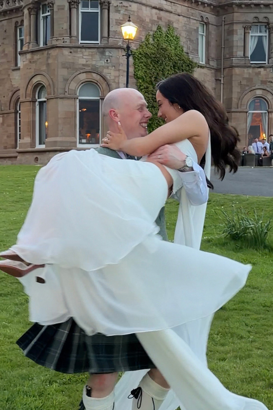 Navae Creative wedding content creator filming a groom lifting his bride outside a castle wedding venue