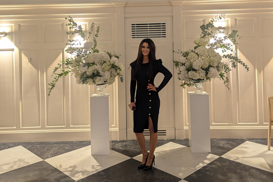Vocals by Suzie standing in an elegant wedding venue with white floral arrangements and arched windows