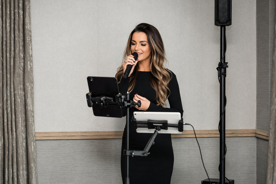 Vocals by Suzie performing live at an indoor wedding or event with microphone, tablet and speaker setup