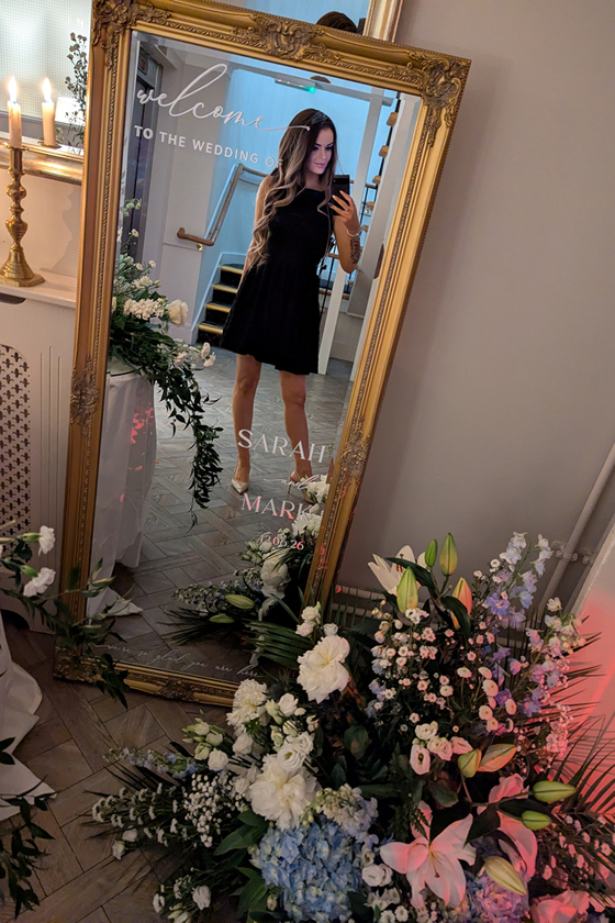 Vocals by Suzie taking a mirror selfie in a personalised gold wedding mirror surrounded by floral décor