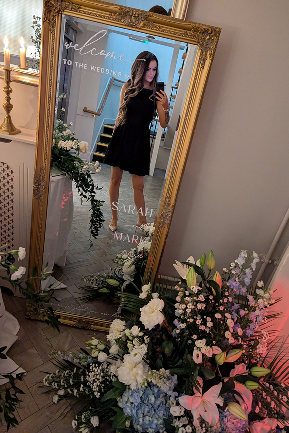 Vocals by Suzie taking a mirror selfie in a personalised gold wedding mirror surrounded by floral décor