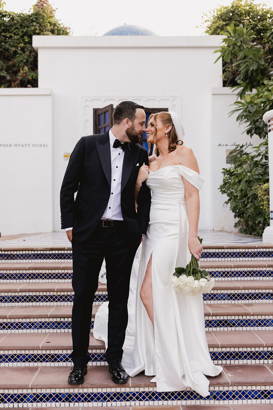 Bride and groom pose together on patterned tiled steps at a luxury Dubai destination wedding venue.