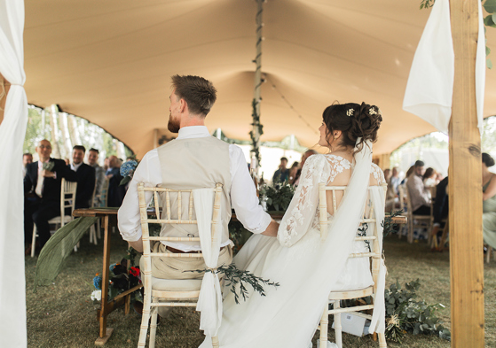Bride and groom seated during their outdoor marquee wedding reception, captured by Jay Franco Films