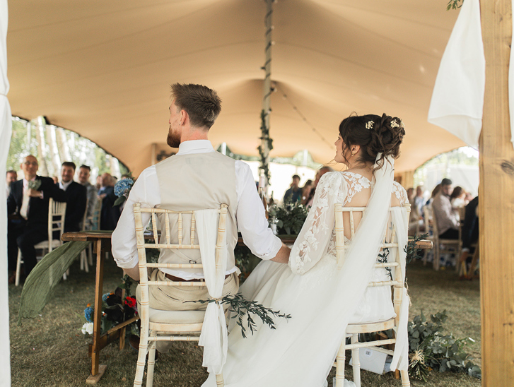 Bride and groom seated during their outdoor marquee wedding reception, captured by Jay Franco Films