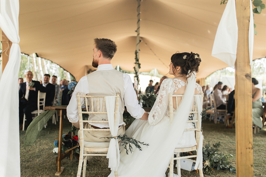 Bride and groom seated during their outdoor marquee wedding reception, captured by Jay Franco Films