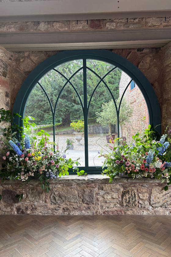Agapanthus Flower Studio floral installation framing an arched window at a Scottish wedding venue