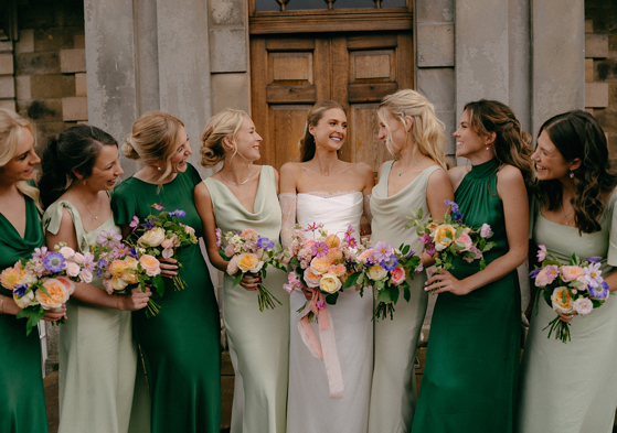 Bride and bridesmaids in green dresses holding colourful bouquets by Agapanthus Flower Studio