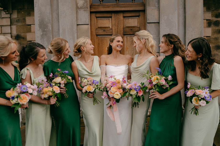 Bride and bridesmaids in green dresses holding colourful bouquets by Agapanthus Flower Studio