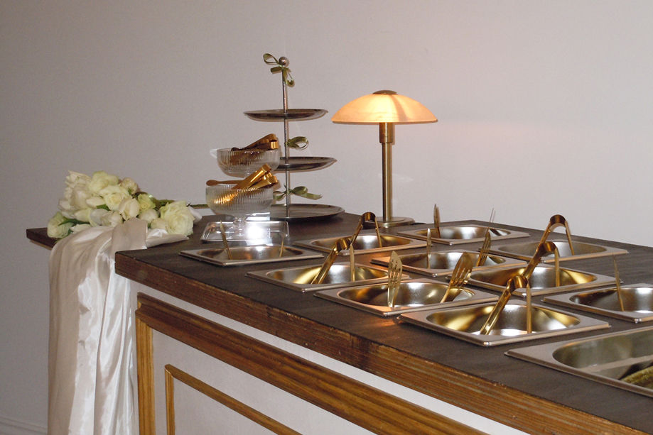 Wedding hot food buffet by Bramble & Brie with gold serving utensils and white floral styling