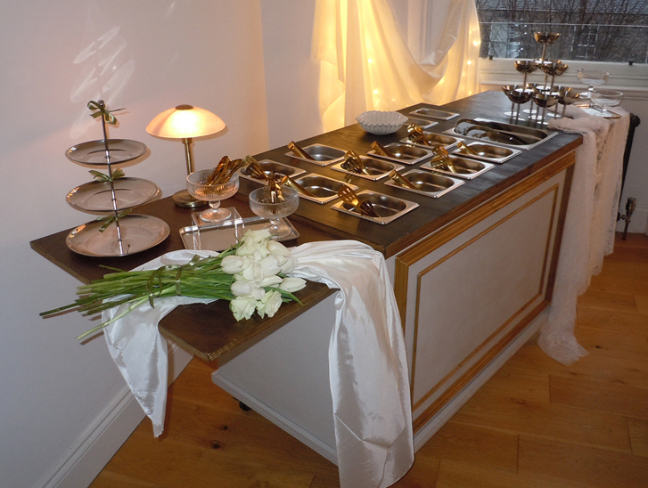 Bramble & Brie indoor wedding grazing cart with gold serving dishes, white flowers and warm ambient lighting