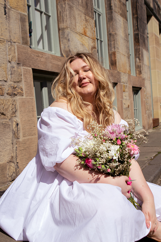 Bride in a short white wedding dress holding a colourful bouquet during a sunny Edinburgh city wedding photoshoot by Rscott_shoots.