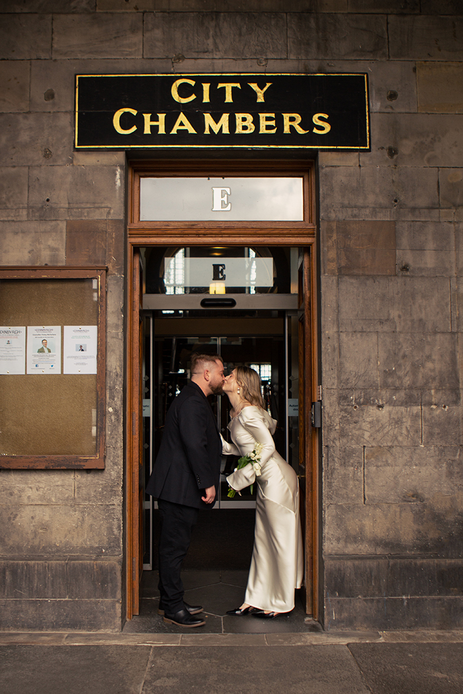 Newlyweds kissing in the doorway of Edinburgh City Chambers after their intimate registry office wedding ceremony, photographed by Rscott_shoots.