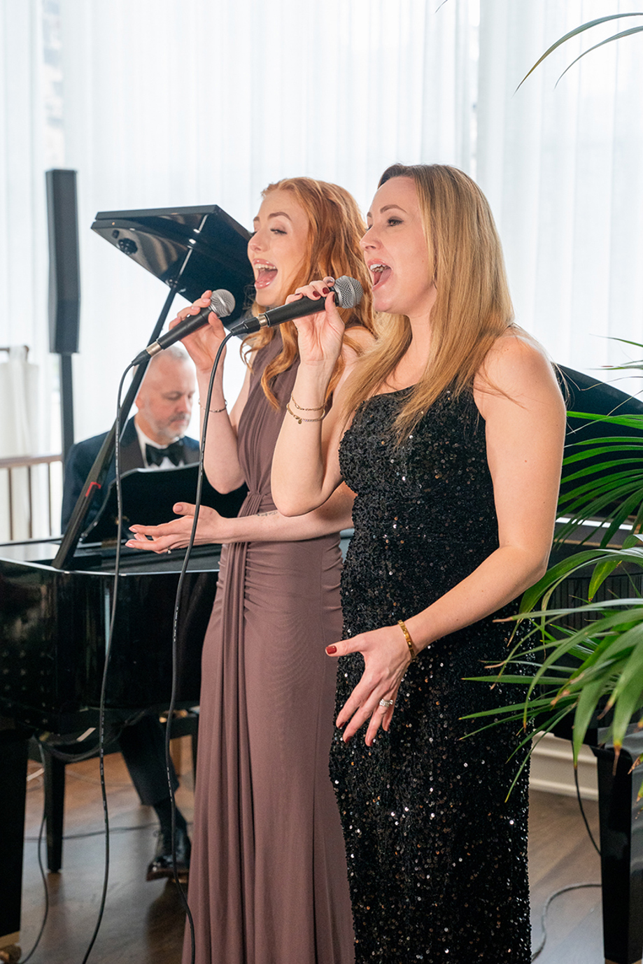 Copper Blonde singers performing beside a grand piano at a wedding venue