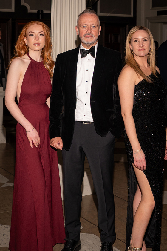 Copper Blonde wedding band trio posing in formal black-tie outfits at a wedding venue