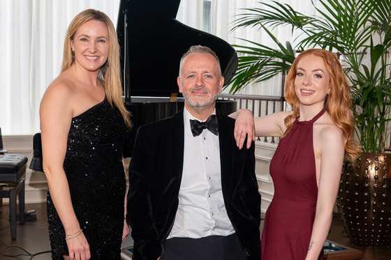Copper Blonde wedding band trio posing beside a grand piano ahead of a live wedding performance