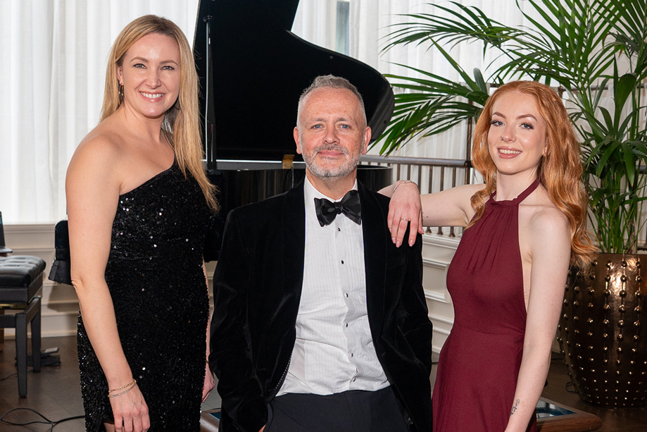 Copper Blonde wedding band trio posing beside a grand piano ahead of a live wedding performance