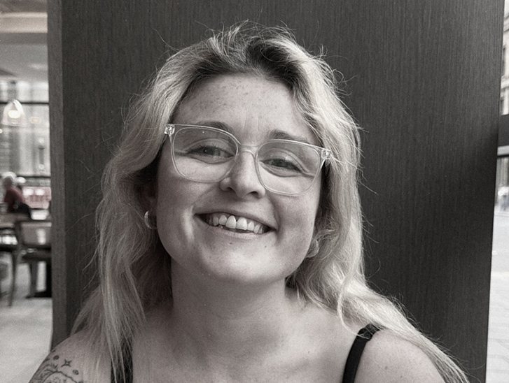 Black-and-white portrait of the smiling With Vic wedding content creator wearing glasses.